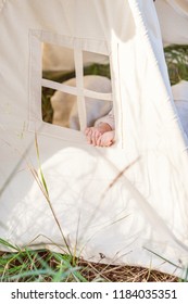 Toddler Playing In Cotton Teepee With Window, Decorated With Flags. One Year Cute Boy In A Teepee Outdoors.