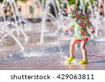 Toddler playing with small fountains on the urban plaza.