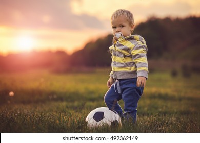 Toddler Playing With A Soccer Ball In The Sunset