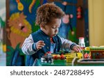 Toddler playing with a train set at nursery, kinder garden. Multi ethnic boy at playtime. 