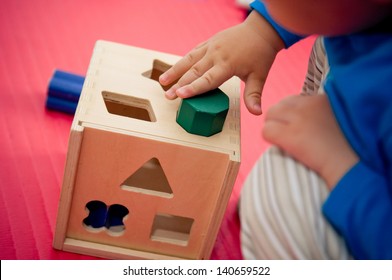 Toddler Playing With Wooden Shape Sorter