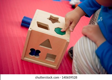 Toddler Playing With Wooden Shape Sorter