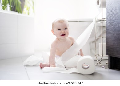 A Toddler Ripping Up Toilet Paper In Bathroom