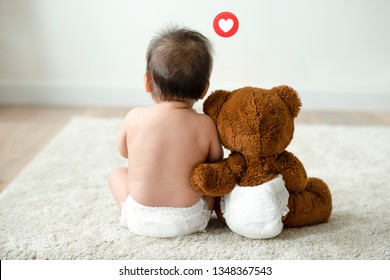 Toddler sitting beside his teddy bear