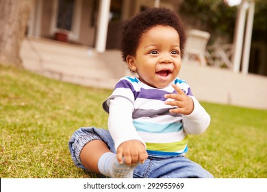 Toddler Sitting On The Grass In A Garden