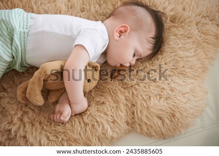 Toddler, sleep and home with teddybear in sofa to rest, tired and relax with dummy and dream. High angle, baby, and nap in couch for child development, growth and innocent with peace for bedtime.