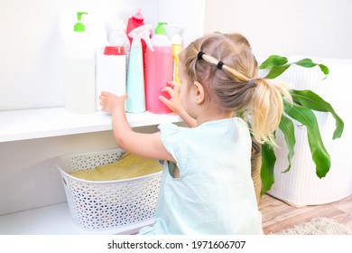 Toddler Touches Bottles Of Household Chemicals, Household Cleaning Products. Dangerous Situation