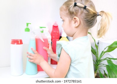 Toddler Touches Bottles Of Household Chemicals, Household Cleaning Products. Dangerous Situation