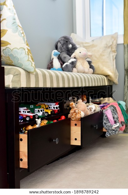 Toddler toy storage solutions in\
window bench in living room for easy clean up and tidy\
living
