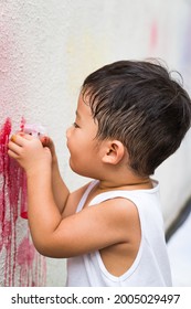 A Toddler Using Spray Bottle To Paint On The Wall