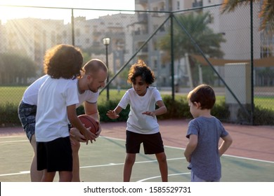 Toddler,brothers And Their Trainer Playing Basketball In Park.Group Of Kids Play Basketball On Playground On Summer Time.Happy Family Playing Basketball Together.Different Age Kids Playing Basketball