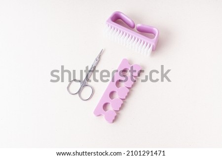 Toe divider, scissors, and brush on light background. Set for pedicure or manicure. Professional tools
