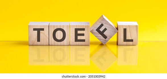 Toefl Word Is Made Of Wooden Blocks Lying On The Yellow Table. Education Concept. Toefl - Short For Test Of English As A Foreign Languages