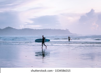 Tofino Vancouver Island September 2019, surfers on the beach of Cox bay during sunset at fall season with orange colors and fog above the ocean