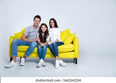 Together Forever. Portrait Of A Beautiful Happy Family Sitting On A Yellow Couch At Home In Their Living Room.