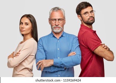 Together we can do everything. Photo of family: lovely woman, bearded adult male and grey haired mature man stand backs with crossed hands, have self confident expressions isolated on white background