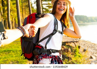 Together we will make it through. Modern young couple holding hands and moving up while hiking together in the woods