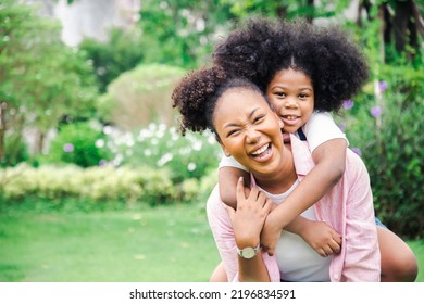 Togetherness Lovely Concept. African Daughter Hugging Her Mum From The Back, Sitting On Grass At Garden, Showing Her Love, Empty Space. Happiness In Last Holiday