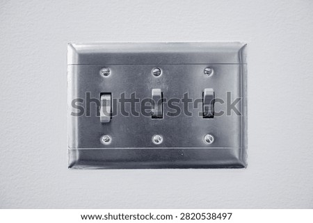 Toggle light switches in on-off mode. The electrical light switches is mounted on the white wall inside a house.