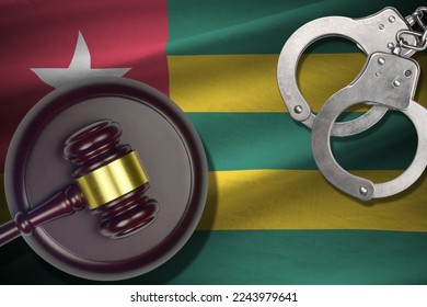 Togo flag with judge mallet and handcuffs in dark room. Concept of criminal and punishment, background for guilty topics