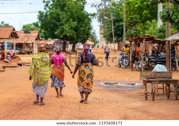 Togoville village in Togo. Women walking in\
African outfits in the village. Voodoo religion in Togo, West\
Africa. Togoville and Lomé voodoo\
markets.