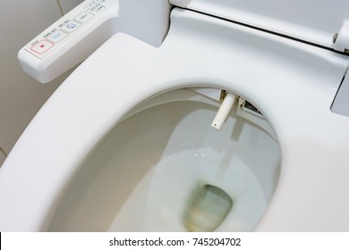 Toilet bowl with electronic control bidet. Water sprays from the toilet bowl. A cleansing jet of water designed to cleanse the anus of the user of this bidet-style toilet.