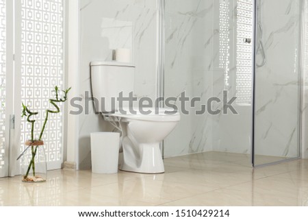 Toilet bowl near shower stall in modern bathroom interior