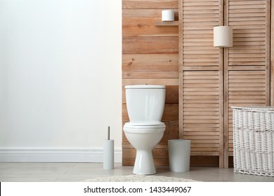Toilet bowl near wooden wall in modern bathroom interior. Space for text
