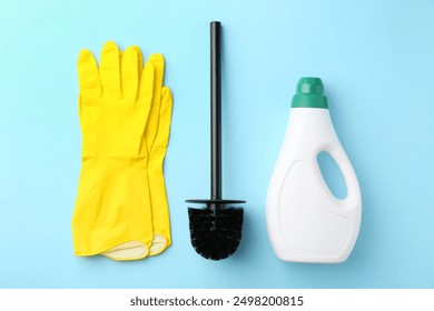 Toilet brush, yellow gloves and cleaning product on light blue background, flat lay - Powered by Shutterstock