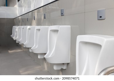 Toilet men's room. Row of outdoor urinals men public toilet, Closeup white urinals in men's bathroom, design of white ceramic urinals for men in toilet room. Empty advertisement in public toilet