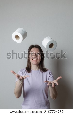 toilet paper concept. beautiful girl in a good mood, smiling, throwing up a lot of toilet paper rolls, has a happy look, has fun