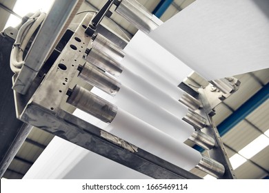 A toilet paper making machine producing toilet and bathroom paper rolls. Paper and tissue manufacturers factory and engineered machinery. Mass produced bathroom products. - Shutterstock ID 1665469114