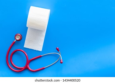 Toilet paper roll and stethoscope for proctology diseases concept on blue background top view mockup
