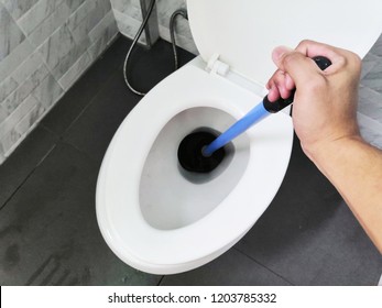 Toilet repair by hand Plumbing.A plumber uses a plunger to unclog a toilet.Toilet Plunger.