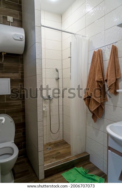 Toilet, shower and electric water heater in
bathroom. Electric Boiler In hotel. Small compact bathroom divided
with shower curtain and
toilet