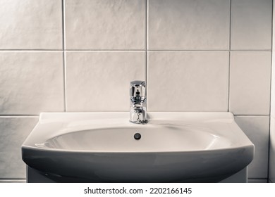 Toilet sink. Bathroom faucet, water tap and WC basin. Dramatic moody light with dark shadows. Public restroom. Grunge rustic or dirty old lavatory home or in hotel. Bad hygiene, wash hands in washroom - Shutterstock ID 2202166145