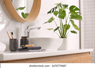 Toiletries and stylish vessel sink on light countertop in modern bathroom