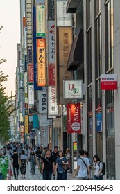 Tokyo, Chuo Ward - August 26, 2018: People walking by Ginza streets with colorful billboards, restaurants and shops. Weekend afternoon when central Chuo Dori street is closed to automobile traffic