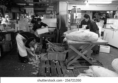 TOKYO - DECEMBER 24, 2014: Fishmonger prepare frozen tuna in their stall at the Tsukiji Fish Market in Tokyo, Japan. The Tsukiji fish market is the biggest wholesale seafood market in the world.