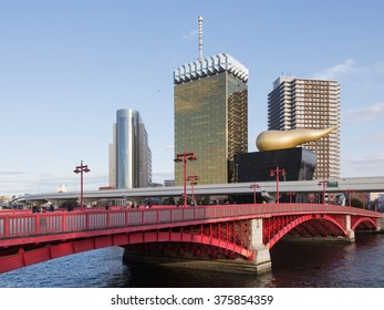Tokyo - January 28 2015: Modern architecture Asahi Beer Hall (a.k.a. Super Dry Hall, or Flamme d'Or), and people go on the red pedestrian bridge over the Sumida River January 28, 2015, Tokyo, Japan