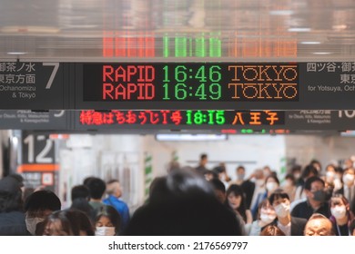 Tokyo, Japan - 04.2022: Crowd Of Commuter Rush To Board The Train To Commute Home During Evening Rush Hour At Shinjuku Station With LED Sign Board Showing Train Schedule And Platform Number