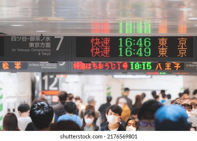 Tokyo, Japan - 04.2022: Crowd Of Commuter Rush To Board The Train To Commute Home During Evening Rush Hour At Shinjuku Station With LED Sign Board Showing Train Schedule And Platform Number