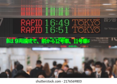 Tokyo, Japan - 04.2022: Crowd Of Commuter Rush To Board The Train To Commute Home During Evening Rush Hour At Shinjuku Station With LED Sign Board Showing Train Schedule And Platform Number