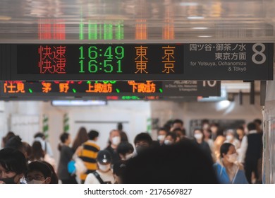 Tokyo, Japan - 04.2022: Crowd Of Commuter Rush To Board The Train To Commute Home During Evening Rush Hour At Shinjuku Station With LED Sign Board Showing Train Schedule And Platform Number