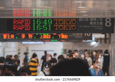 Tokyo, Japan - 04.2022: Crowd Of Commuter Rush To Board The Train To Commute Home During Evening Rush Hour At Shinjuku Station With LED Sign Board Showing Train Schedule And Platform Number