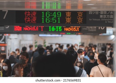 Tokyo, Japan - 04.2022: Crowd Of Commuter Rush To Board The Train To Commute Home During Evening Rush Hour At Shinjuku Station With LED Sign Board Showing Train Schedule And Platform Number