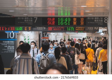 Tokyo, Japan - 04.2022: Crowd Of Commuter Rush To Board The Train To Commute Home During Evening Rush Hour At Shinjuku Station With LED Sign Board Showing Train Schedule And Platform Number