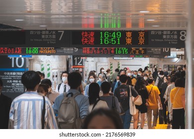 Tokyo, Japan - 04.2022: Crowd Of Commuter Rush To Board The Train To Commute Home During Evening Rush Hour At Shinjuku Station With LED Sign Board Showing Train Schedule And Platform Number