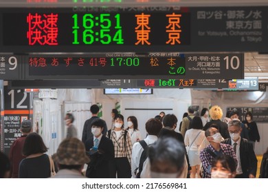 Tokyo, Japan - 04.2022: Crowd Of Commuter Rush To Board The Train To Commute Home During Evening Rush Hour At Shinjuku Station With LED Sign Board Showing Train Schedule And Platform Number