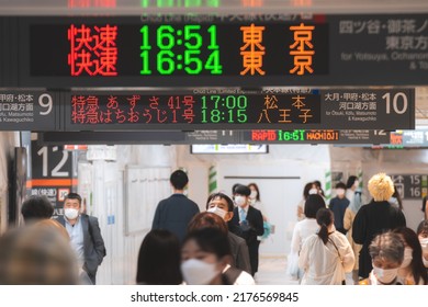 Tokyo, Japan - 04.2022: Crowd Of Commuter Rush To Board The Train To Commute Home During Evening Rush Hour At Shinjuku Station With LED Sign Board Showing Train Schedule And Platform Number